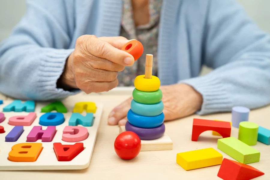 Elderly woman stacks colored rings to help rehabilitate stages of dementia symptoms.