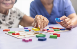 Caregiver and senior woman playing wooden shape puzzles game for dementia prevention